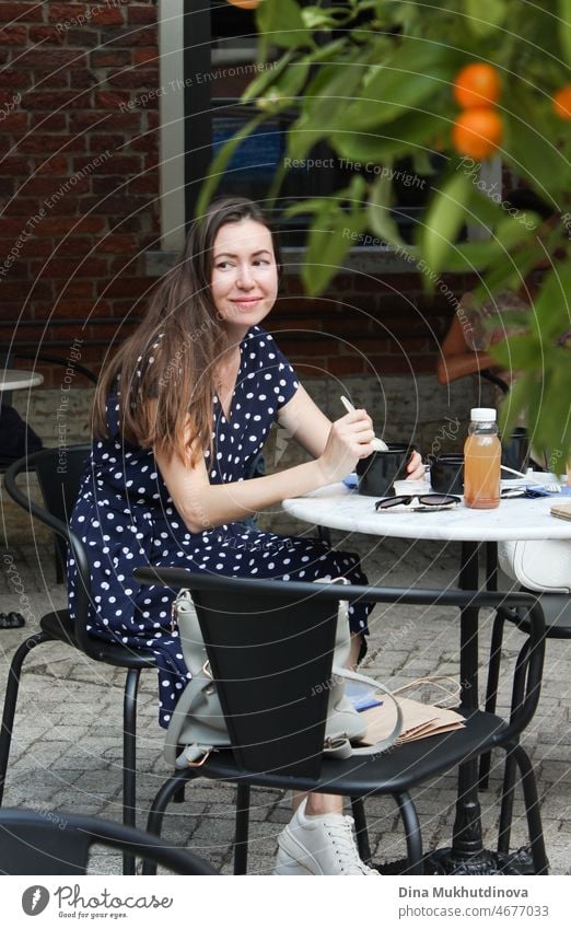 Candid Porträt der Frau essen im Café Terrasse, lächelnd. Authentischer Lebensstil der Millennial-Frau im Sommer in der Stadt. schön sich[Akk] entspannen Kaffee