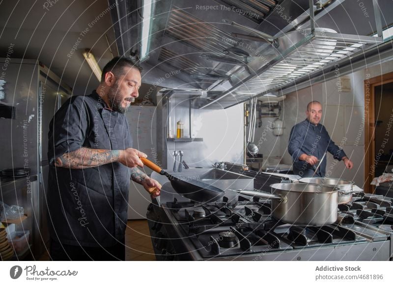 Koch beim Flambieren in der Bratpfanne Küchenchef flambieren Feuer Technik Fähigkeit Restaurant Arbeit vorbereiten kulinarisch Abfertigungsschalter Job