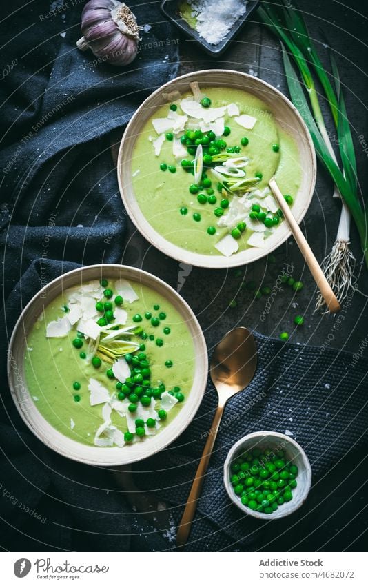 Erbsencreme auf dunklem Tisch Sahne Suppe kulinarisch Gastronomie Küche Püree Mahlzeit gesunde Ernährung Lebensmittel grün Zwiebel Löffel Serviette dienen