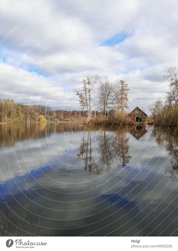 Seeufer mit Haus und Bäumen spiegelt sich im See Moorsee Hücker Moor Gebäude Himmel Wolken Sonnenschein Sonnenlicht Idylle idyllisch Frühling