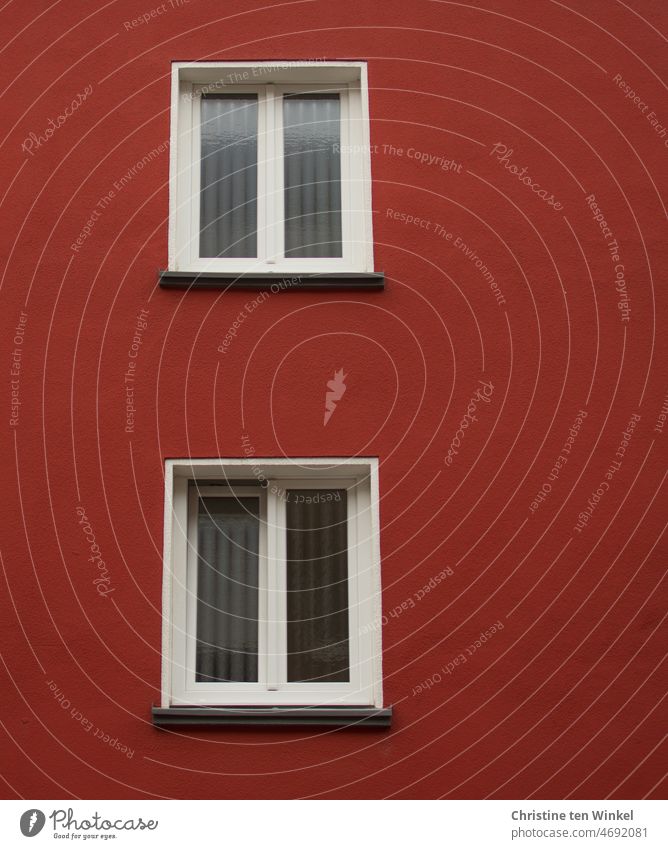 Zwei Fenster mit weißen Rahmen  und die rote Fassade eines Mehrfamilienhauses Fensterrahmen Fensterscheibe Putzfassade Milchglasscheibe Wand Haus Architektur