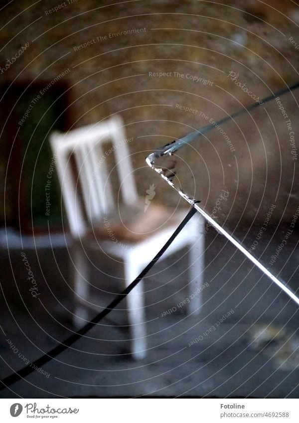 Es scheint fast so, als würden die spitzen Stücke der zerbrochenen Fensterscheibe den alten Holzstuhl im Hintergrund aufspießen wollen. lost places kaputt