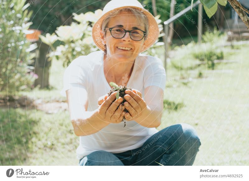 Porträt einer alten Frau bei der Gartenarbeit, die in der Freizeit in die Kamera lächelt. Freizeitbeschäftigung zu Hause. Rettet den Planeten, indem sie Pflanzen pflanzt. Planet betrifft. Reife Menschen arbeitet zu Hause