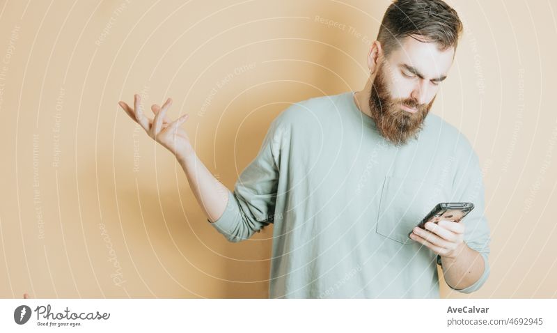 Junger Mann bärtigen Hipster-Stil Lesung Telefon besorgt über eine neue, gelben Hintergrund. Emotion über den Erhalt einer guten neuen, abnehmbaren Hintergrund mit Kopie Raum. Junge Menschen soziales Netzwerk