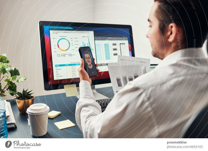 Mann Unternehmer mit Geschäftsgespräch, Video-Chat auf Mobiltelefon. Geschäftsmann arbeitet mit Daten, Diagrammen und Grafiken auf dem Computer-Bildschirm