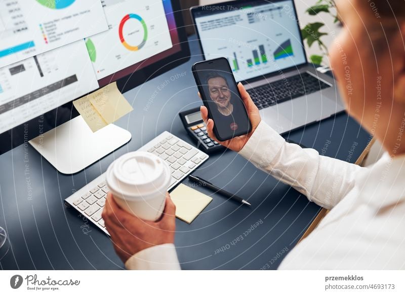 Unternehmerin bei einem geschäftlichen Video-Chat auf einem Smartphone. Geschäftsfrau arbeitet mit Daten auf Diagrammen, Graphen und Diagrammen auf dem Computerbildschirm