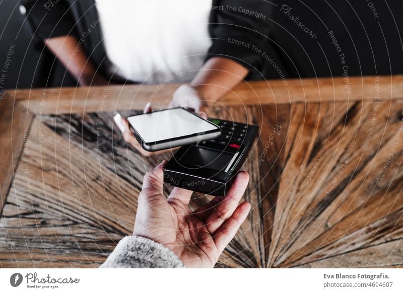 Nahaufnahme einer Frau beim kontaktlosen Bezahlen mit dem Mobiltelefon in einem Cafe. unkenntlich Kontakt weniger Zahlung Handy Technik & Technologie Frauen