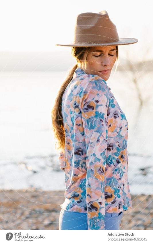 Rätselhafte Frau mit Hut am Strand Stil Wasser Fluss Natur rätselhaft feminin Sommer Augen geschlossen Landschaft Küste Ufer sensibel Kopfbedeckung Kopfschmuck