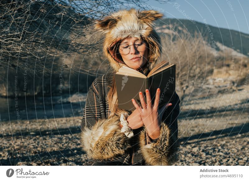 Dame in Pelzmütze mit Buch am Seeufer Frau lesen Fuchs Hut Fluss Verschlussdeckel Küste Stil Stein Fussel Wasser Fell natürlich Kopfbedeckung Zeitvertreib