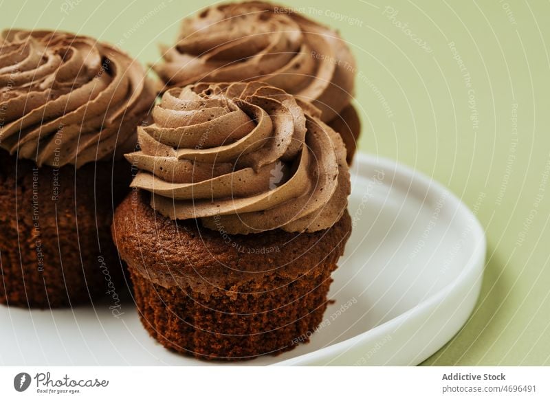 Schokoladen-Cupcakes mit Zuckerguss auf einem Teller Dessert süß Konfekt Gebäck Konditorei Belag Leckerbissen Lebensmittel frisch geschmackvoll lecker