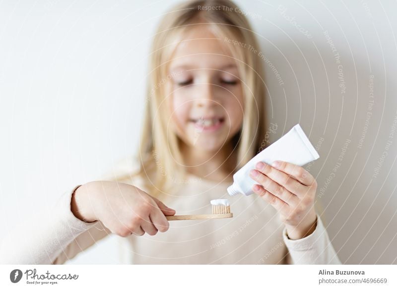 Nettes kleines Mädchen hält Hände Öko-Bambus-Zahnbürste auf beige Hintergrund. Nachhaltiges Lebenskonzept. Speichern Sie den Planeten für unsere Kinder