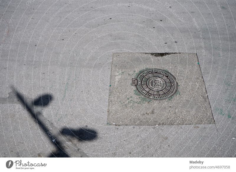 Runder Kanaldeckel in ausgebessertem grauen Asphalt im Sommer bei Sonnenschein in den Straßen von Adapazari in der Provinz Sakarya in der Türkei Großstadt