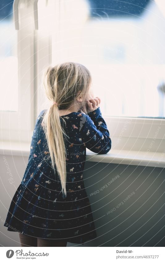 Mädchen schaut aus dem Fenster Kind blicken beobachten schauen sehnsüchtig eingesperrt Kindheit Quarantäne Ängste Zukunft Gedanken