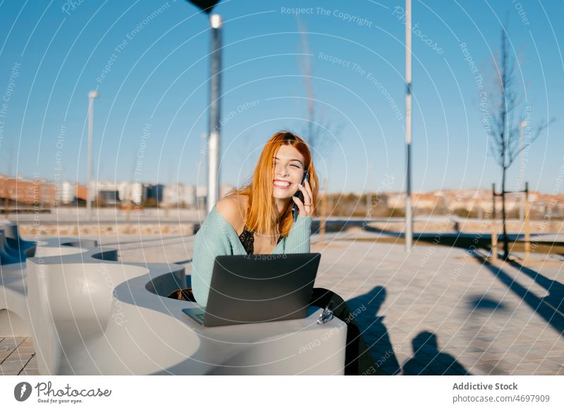 Fröhliche Frau beim Telefonieren auf der Straße Smartphone Telefonanruf Gespräch Kommunizieren Laptop trendy diskutieren Großstadt Vorschein charmant Dame