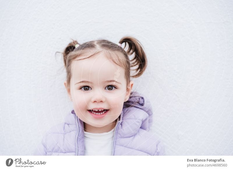 Porträt der schönen kaukasischen zwei Jahre altes Baby-Mädchen lächelnd über weißen Hintergrund. Kindheit im Freien Großstadt Mantel kalt Winter Kaukasier