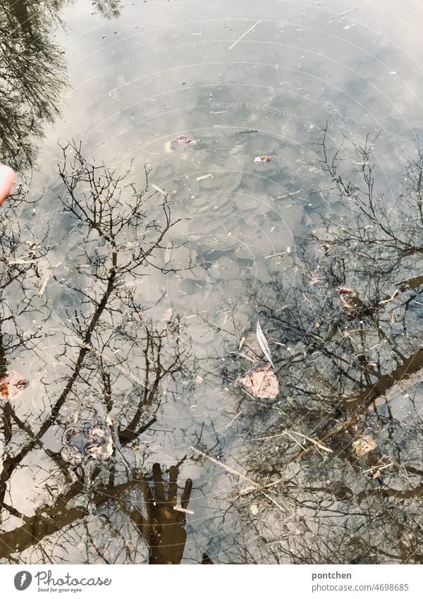 Eine Hand spiegelt sich im wasser. Mensch und Natur. Eingriff in die Natur Wasser hand spiegelung Mensch und natur teich tümpel klimawandel