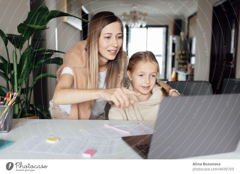 Weiße Familie arbeitet und lernt online zu Hause und mit Laptop. Fernunterricht oder Fernstudium für Kinder. Hübsche, elegante Schülerin, die während der Coronavirus-Covid-19-Quarantäne und der sozialen Distanzierung Hausaufgaben in Mathematik macht