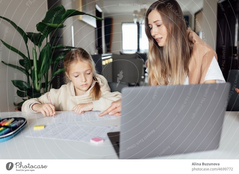 Weiße Familie arbeitet und lernt online zu Hause und mit Laptop. Fernunterricht oder Fernstudium für Kinder. Hübsche, elegante Schülerin, die während der Coronavirus-Covid-19-Quarantäne und der sozialen Distanzierung Hausaufgaben in Mathematik macht