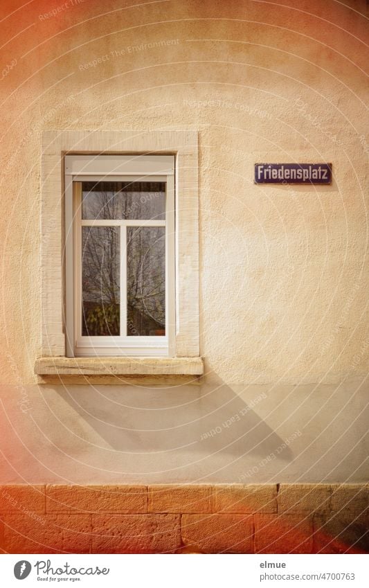 Straßennamenschild  - Friedensplatz -  an einer Hauswand neben einem geschlossenen Fenster / Frieden / Hoffnung Adresse Krieg Ukraine Friedenswunsch