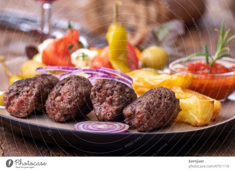 Cevapcici auf einem Teller mit Pommes Frites rustikal Holz Fritten Wein Zwiebel Salat Kebab Fleisch Kartoffel geGrillt Rindfleisch Küche Kofta Türkisch Gericht