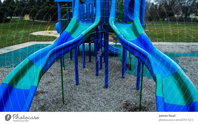 Ein Paar Rutschen im Herbst im örtlichen Park in Blautönen Spielplatz Sliden Kunststoff Gerät spielen Spaß Gras grün blau im Freien Spielen Hintergrund alt