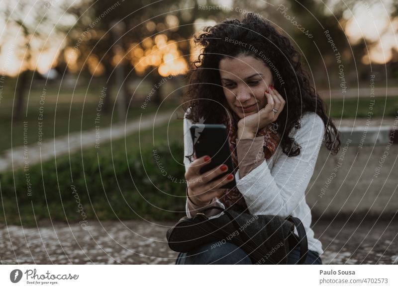 Frau mit Smartphone 30-45 Jahre Neugier lockig Farbfoto schön Haare & Frisuren Zentralperspektive Junge Frau Erwachsene Mensch Lifestyle Außenaufnahme feminin