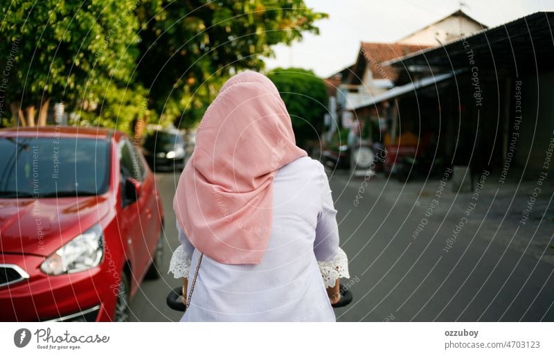 Rückansicht junge asiatische muslimische Frau beim Radfahren auf der Straße. Junge Frau mit Kopftuch auf dem Fahrrad. Sport Islam reisen Aktion Übung Freude