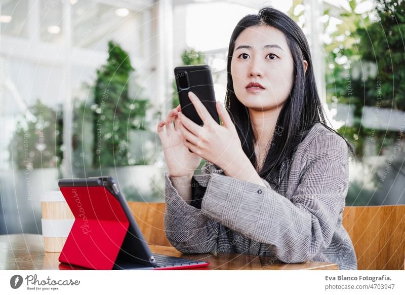 professionelle chinesische Unternehmerin, die in der Cafeteria am Handy arbeitet. Technologie, Lebensstil Chinesisch asiatisch Frau Laptop Technik & Technologie