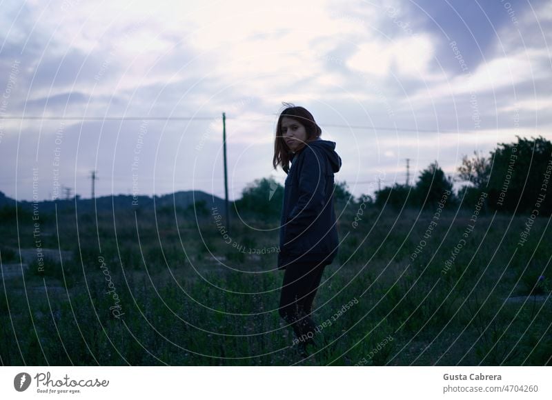 Frau geht bei Sonnenuntergang durch ein Feld. Porträt Gesicht Blick brünett Landschaft Außenaufnahme Schwache Tiefenschärfe Farbfoto Junge Frau Tag