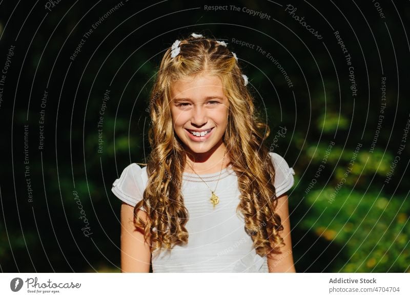 Charmantes Mädchen im Erstkommunionkleid im Park stehend Religion Kommunion friedlich katholisch heilige Kommunion Sommer Lächeln positiv Glück heiter Natur