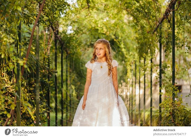 Charmantes Mädchen im Erstkommunionkleid im Park stehend Religion Kommunion friedlich katholisch heilige Kommunion Sommer Lächeln positiv Glück heiter Natur