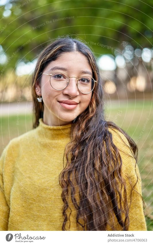 Positive Frau auf dem Rasen sitzend Park feminin Vorschein Stil Lächeln Sommer jung Baum Brille Dame angenehm Pflanze lange Haare Jugend schön Charme Umwelt