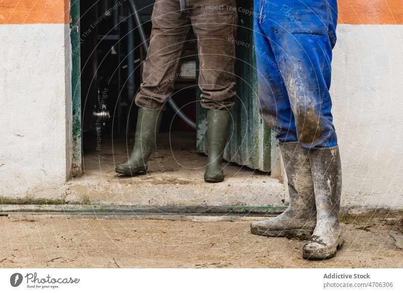 Unbekannte Bauern stehen in der Nähe eines Gebäudes Paar Arbeiter Landwirt Straße Landschaft ländlich dreckig industriell Wehen Job Arbeitsbekleidung Stiefel