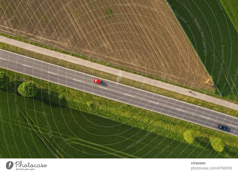 Luftaufnahme einer zweispurigen Straße durch ländliche Gebiete und bewirtschaftete Felder mit Autos. Drohnenaufnahme Dröhnen Fernstraße Ausflug