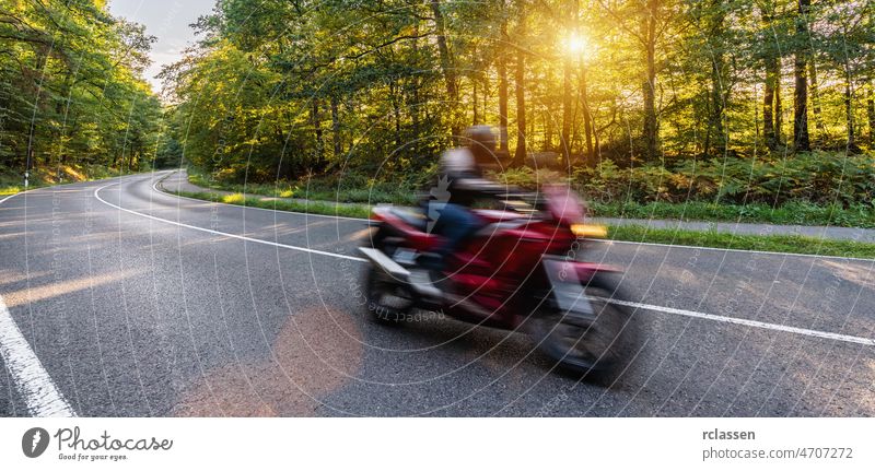 motorrad auf der waldstrasse schnell fahrend. mit spass auf der leeren strasse auf einer motorradtour unterwegs. copyspace für ihren individuellen text.