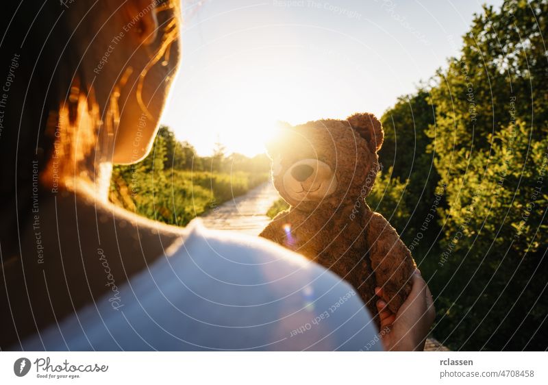 Frau hält Teddybär-Spielzeug bei Sonnenuntergang, Platz für Ihren individuellen Text. Bär Rücken Erwachsener allein Weg Beteiligung schön traurig Schönheit