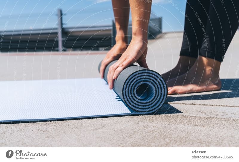 junge frau faltet blaue yoga- oder fitnessmatte nach dem training. keep fit concepts image. copyspace für ihren text. Yoga Unterlage Frau Pilates Kraft Europäer