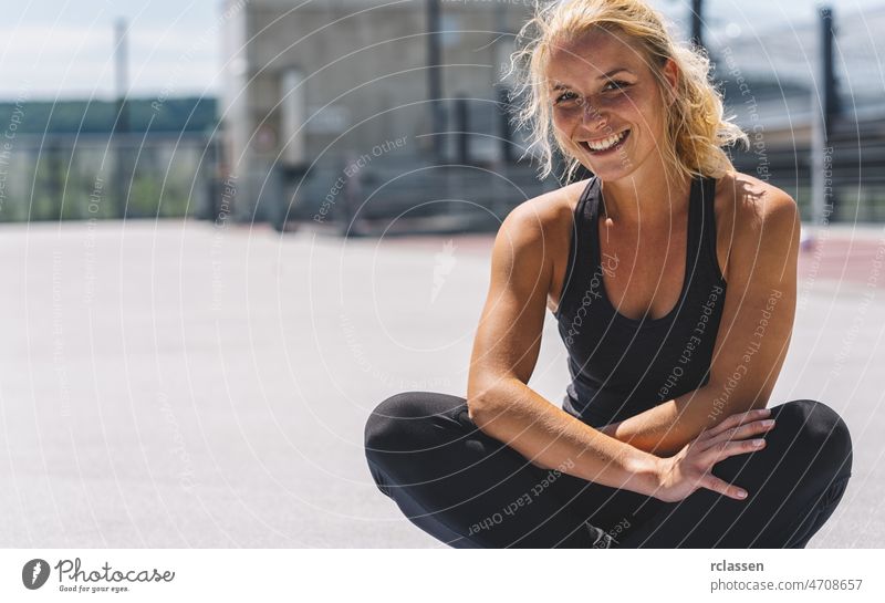 Glückliche attraktive junge Frau in Sportkleidung, die sich nach dem Training entspannt. Fröhliche Stimmung, echte Emotionen, gesunder Lebensstil, lächelnd