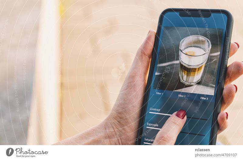 Fotobearbeitung mit Mobiltelefon und Smart-App. Frau stellt Schieberegler ein. Bildbearbeitung, -manipulation, -verbesserung oder -erweiterung mit einem Smartphone. Hinzufügen eines Filters zu einem Foto in einer Social-Media-Anwendung.