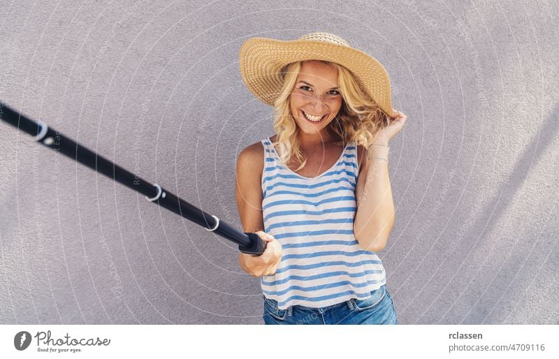 Junges Mädchen lächelnd und verwenden Selfie-Stick, um ein Selfie zu nehmen, im Sommer in der Stadt Straße. Urbanes Leben Konzept. jung Hipster Trave Ausflug