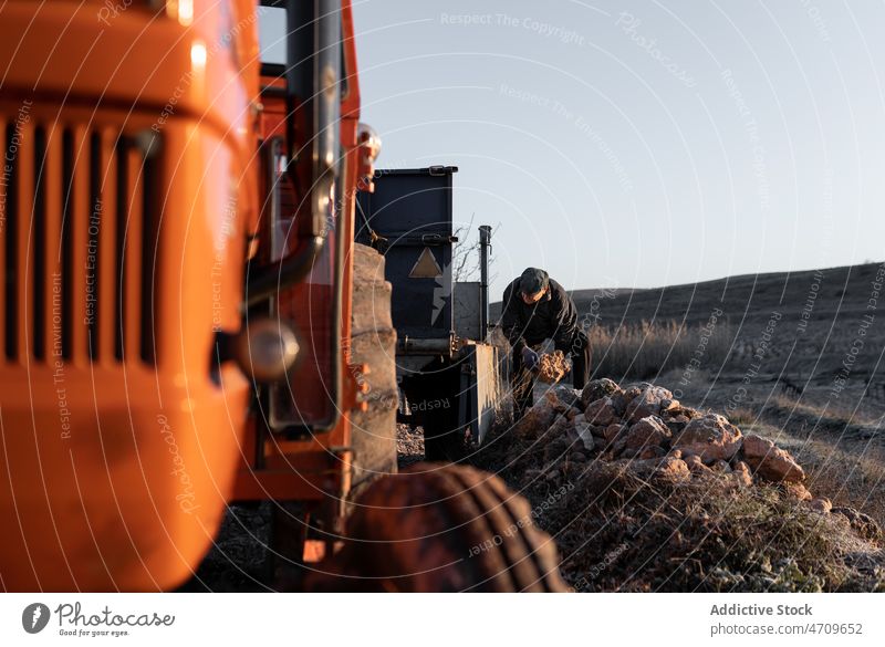 Alter Mann sammelt Steine in einem Traktorwagen in einem ländlichen Tal Landwirt Karre Felsen Arbeit abholen schwer Bauernhof Grasland männlich Ackerbau