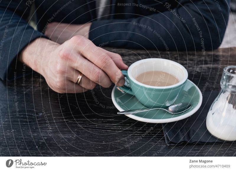 Verheirateter Mann trinkt Kaffee trinken Kaffeetrinken Kaffeepause Kaffeetasse Farbfoto Café verheiratet Kaffeetisch Kaffeebecher Espresso Hand Ring Tisch