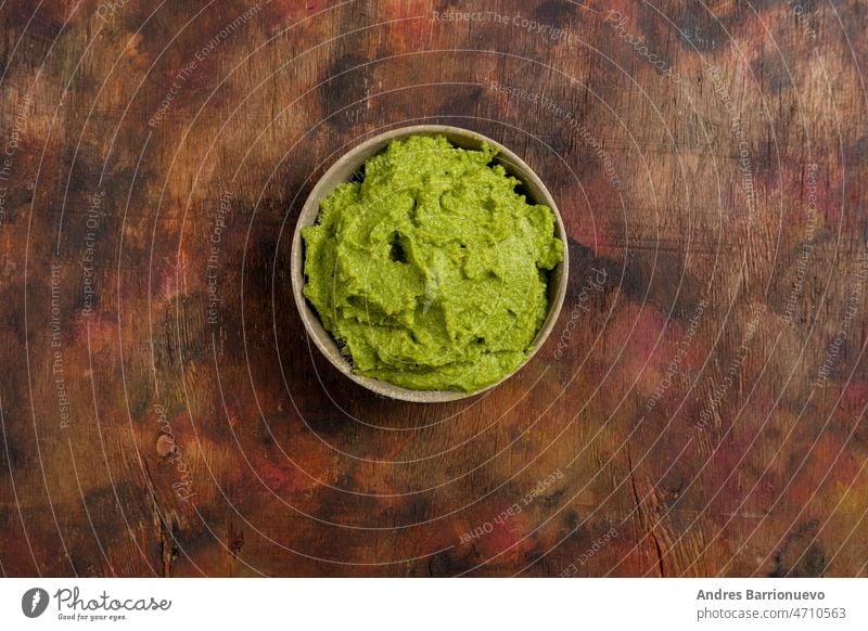 Schale mit frisch zubereiteter frischer Guacamole auf einem Holzhintergrund in Brauntönen. Gesundes Lebensmittel, reich an Omega-3-Fettsäuren, die den Cholesterinspiegel senken. Superfood.