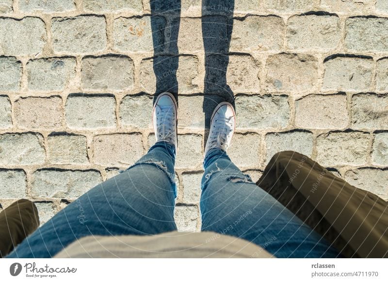 Junge Frau steht auf Kopfsteinpflaster, persönliche Perspektive von oben. pov Menschen Lifestyle Punkt Ansicht Weg Kaukasier jung Egoperspektive Sichtweise