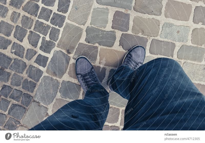 Junger Mann in lässig gekleideten Turnschuhen auf der Straße in einer Altstadt stehend, Point of view shot pov Menschen Lifestyle Punkt Ansicht Sommer Weg