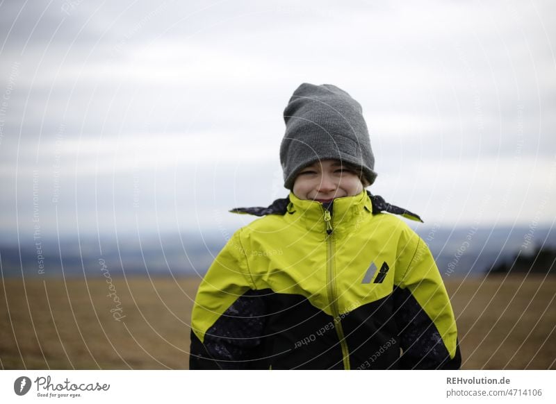 Portrait von einm Jungen mit Mütze Mensch Kind Kindheit Glück Außenaufnahme natürlich Landschaft Jacke authentisch Tag Porträt Oberkörper schmunzeln Wind Wetter