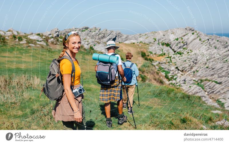 Glückliche junge Frau mit Blick auf die Kamera beim Wandern mit ihren Großeltern Lächeln schauende Kamera Trekking Familie wandern Zusammensein Großvater