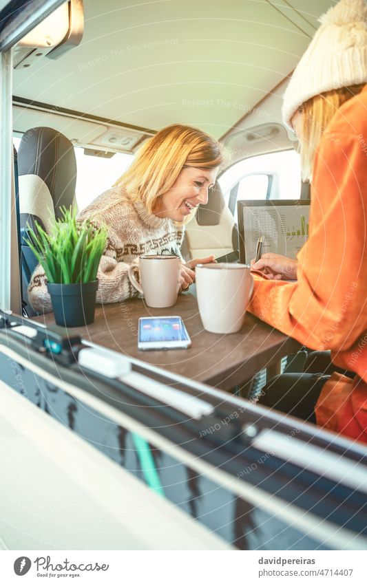 Lachende Frauen bei der Telearbeit in einem Wohnmobil Laptop schreibend Kleintransporter Ausflug Glück abgelegen Arbeit Menschen Tabelle Job arbeiten Business