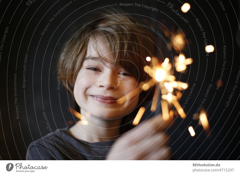 Junge mit einer Wunderkerze lächelt in die Kamera Geburtstag Kind Kindheit Lächeln Glück positiv Fröhlichkeit zufrieden Gesicht Freude im Innenbereich