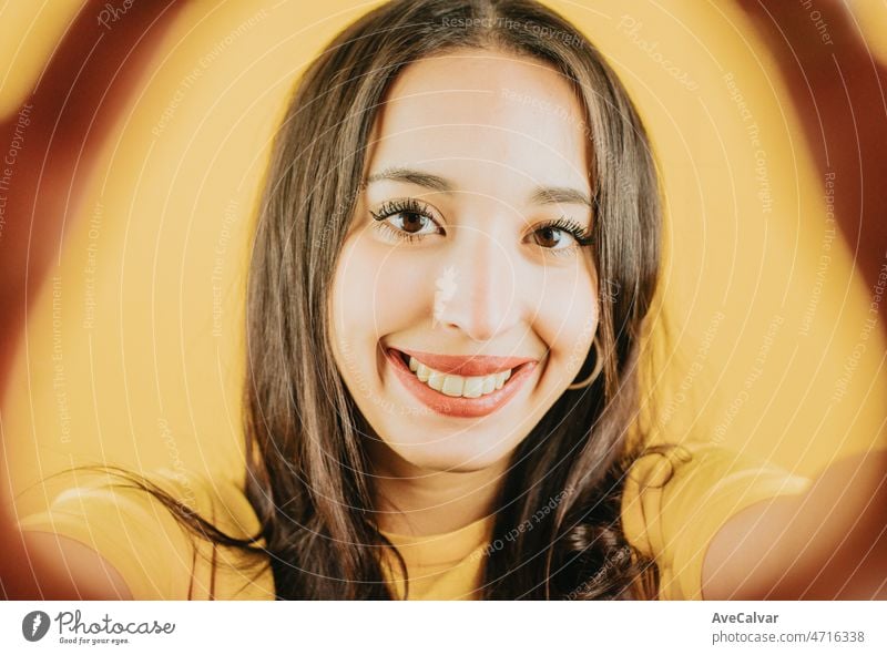 Junge afrikanische Frau hält die Kamera ein Selfie lächelnd in die Kamera glücklich und cool Haltung Konzept posiert isoliert über gelbe Farbe Wand Hintergrund. Tägliche Ausdrücke mit Kopie Raum im Studio.